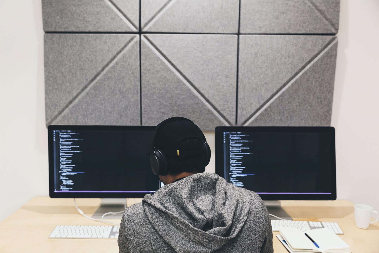 A software developer coding on two monitors